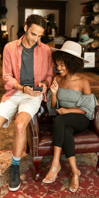 A fashionable couple enjoys shopping for hats in a chic boutique setting.