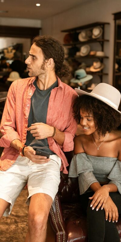 A man and woman enjoying shopping in a stylish boutique, surrounded by hats.